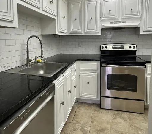 a kitchen with granite countertop white cabinets and stainless steel appliances