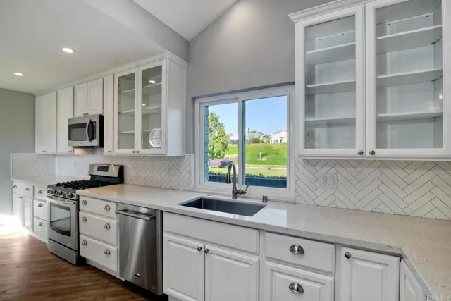 a kitchen with stainless steel appliances white cabinets and a window