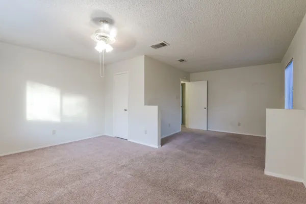 an empty room with a chandelier fan and windows