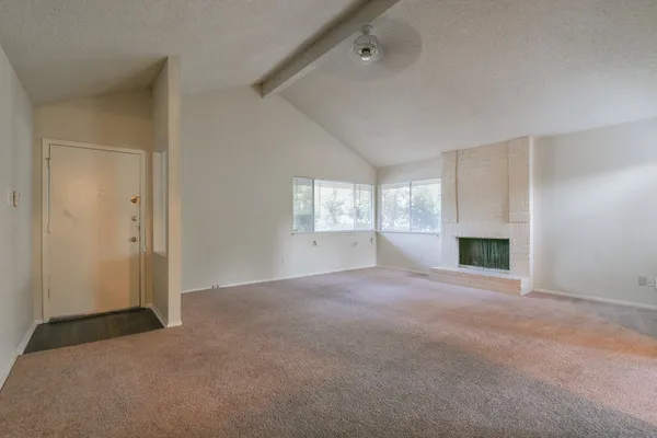 a view of an empty room with a fireplace and a window
