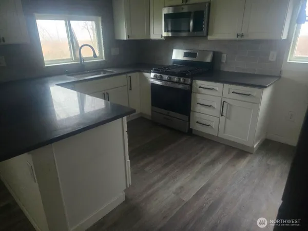 a kitchen with stainless steel appliances granite countertop a stove a sink and a microwave