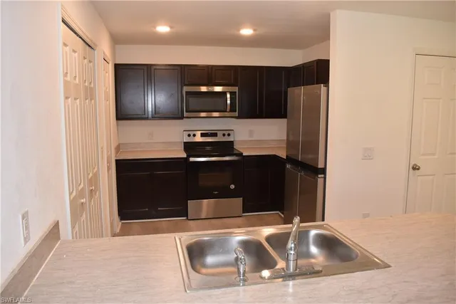 a kitchen with stainless steel appliances wooden cabinets a sink and a refrigerator