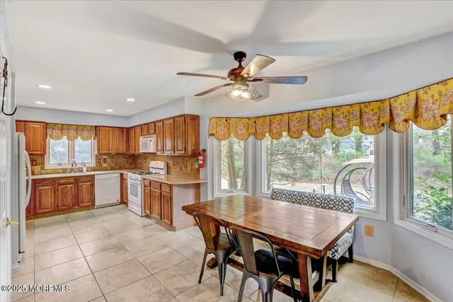 a kitchen with a stove a refrigerator a dining table and chairs with the wooden floor