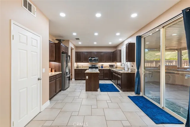 a kitchen with stainless steel appliances granite countertop a stove top oven a refrigerator a sink and dishwasher