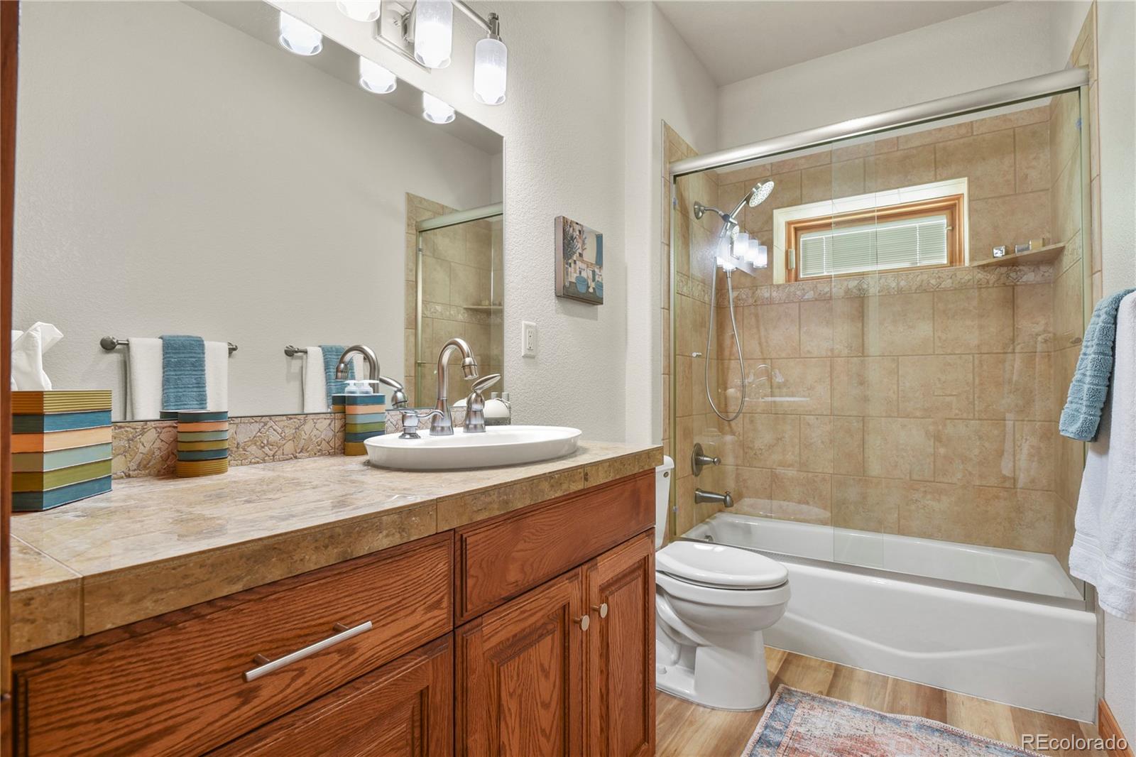 5220 Roundup Ridge Road Colorado Springs, CO 80908 - Photo 32 of 50 a bathroom with a granite countertop sink a toilet a mirror and shower