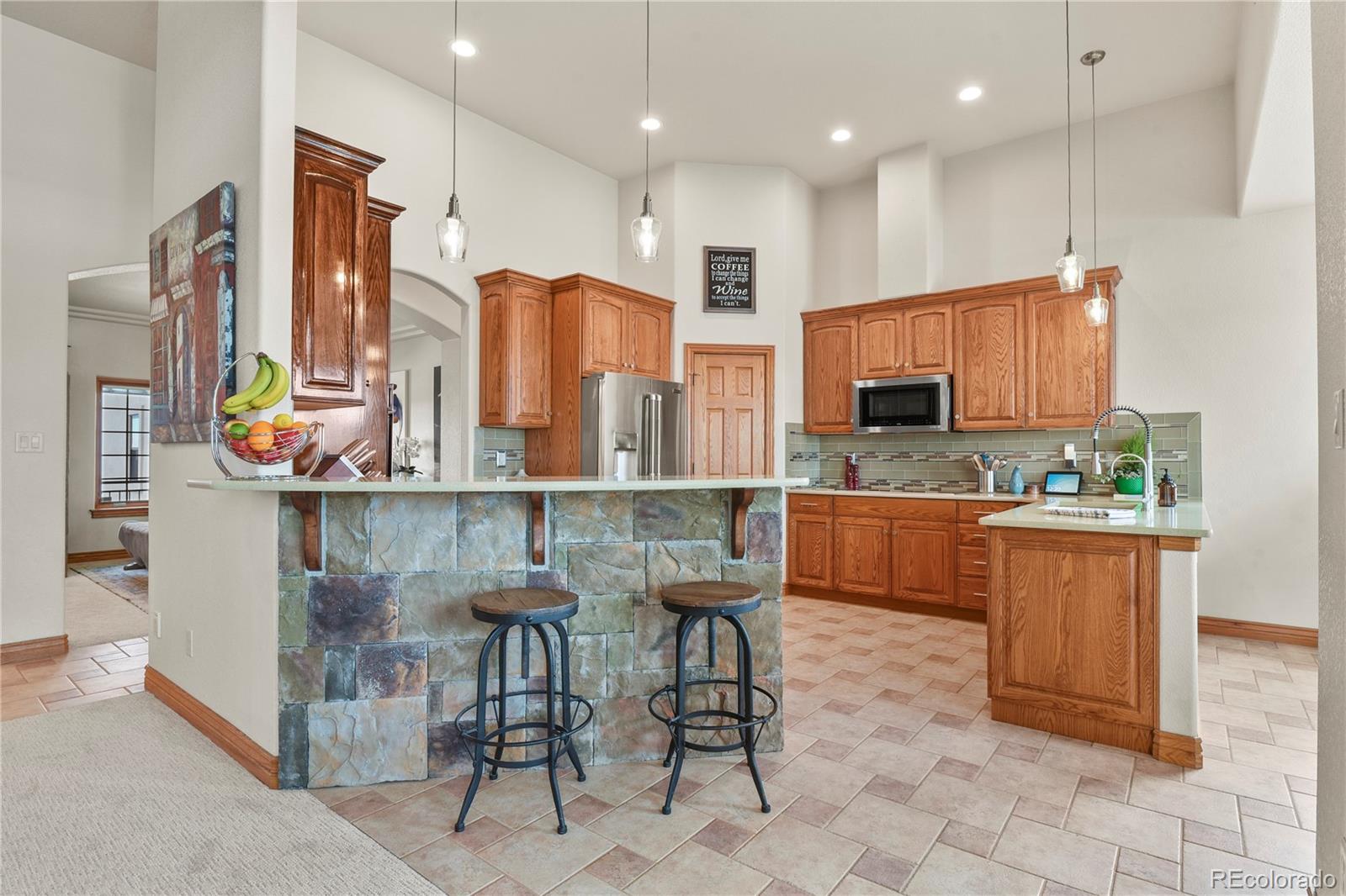 5220 Roundup Ridge Road Colorado Springs, CO 80908 - Photo 8 of 50 a kitchen with stainless steel appliances kitchen island granite countertop a stove a sink and a refrigerator