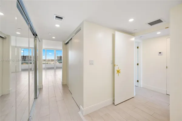 a view of hallway with stainless steel appliances refrigerator and cabinets
