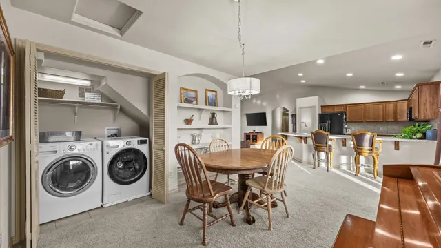 a view of a dining room with furniture a kitchen and chandelier