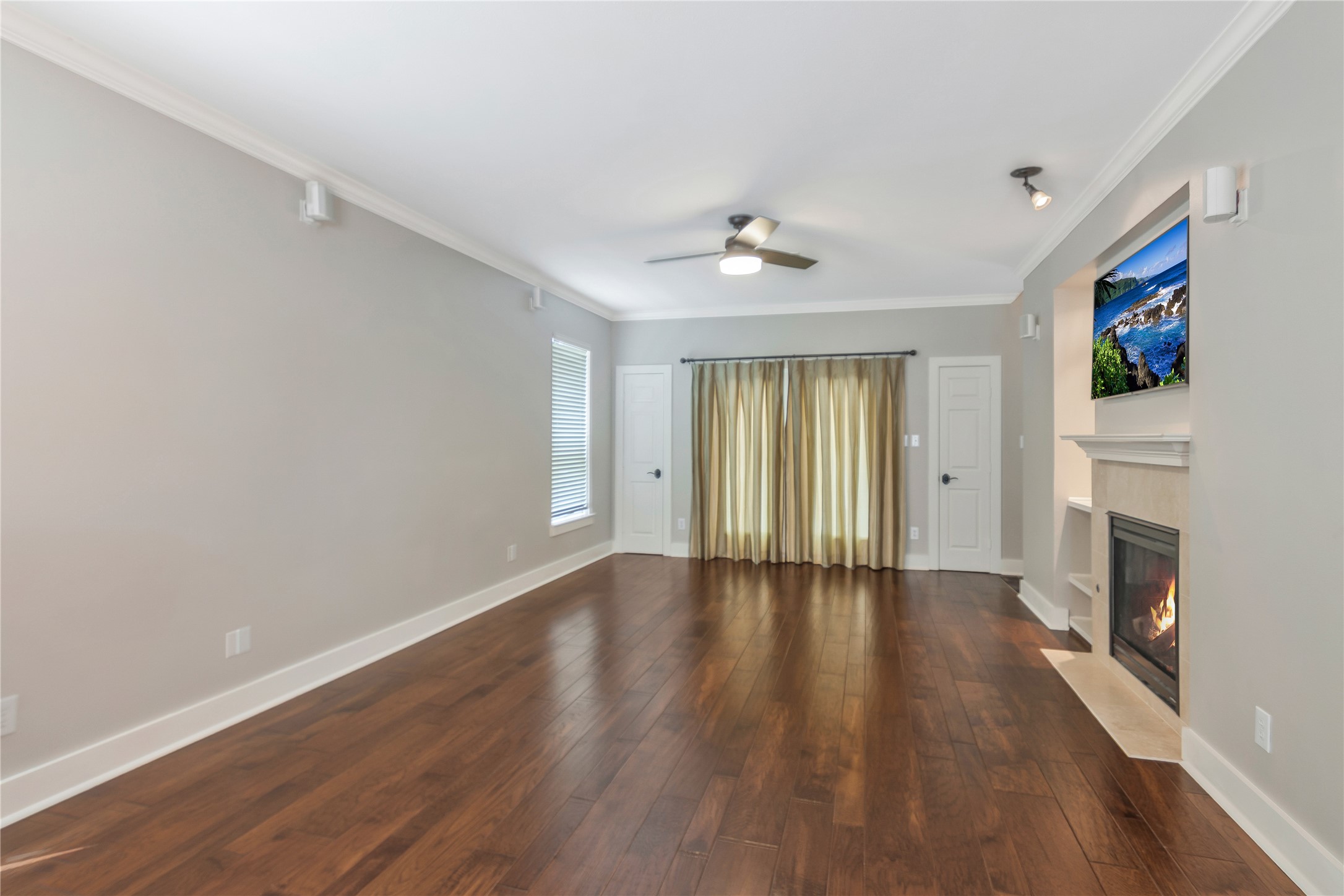 1207 Nagle Street Houston, TX 77003 - Photo 9 of 26 This spacious living room features elegant hardwood flooring, a cozy fireplace, and a ceiling fan. The Neutral walls provide a versatile backdrop, perfect for personal touches.