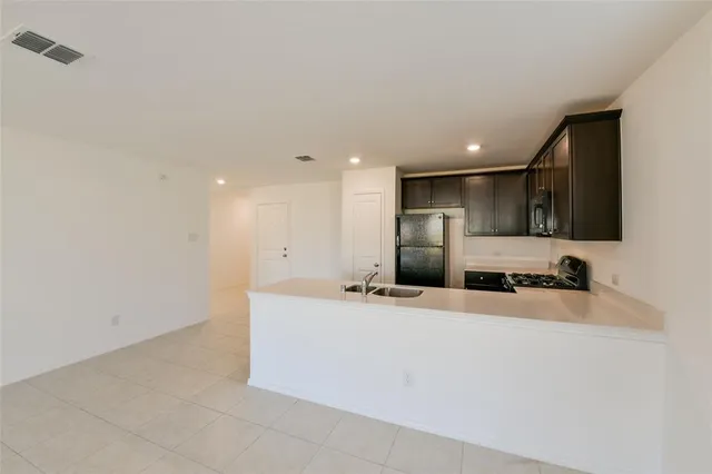 a large white kitchen with kitchen island a sink stainless steel appliances and cabinets