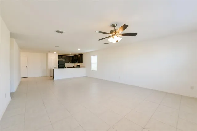 an empty room with a kitchen and a ceiling fan