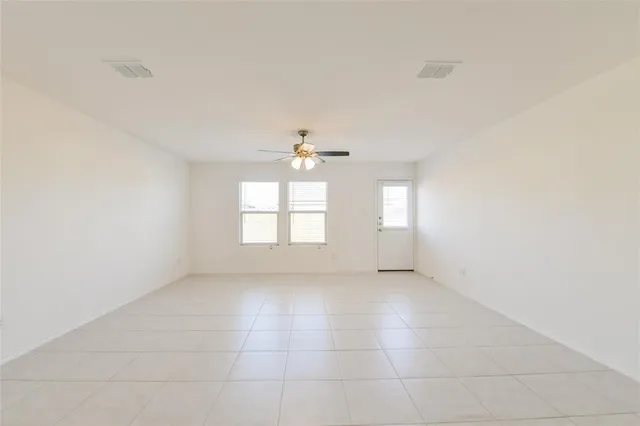 an empty room with windows and ceiling fan