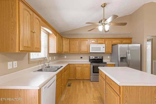 a kitchen with stainless steel appliances a sink a stove a refrigerator cabinets and a large window