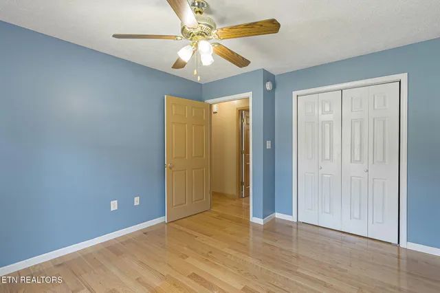 an empty room with wooden floor fan and windows