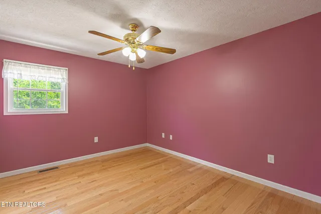 en empty room with a fan and a window