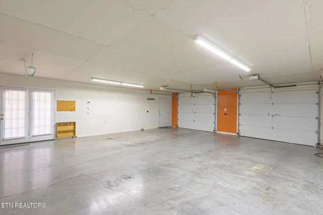 an empty room with chandelier fan and windows