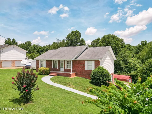 a view of a house with a big yard plants and large trees