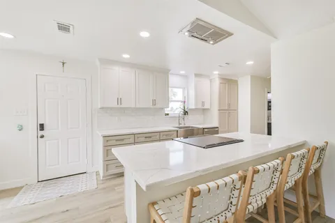 a kitchen with a sink a stove a refrigerator and white cabinets with wooden floor