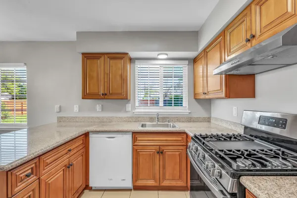 a kitchen with granite countertop a stove a sink dishwasher and cabinets with wooden floor