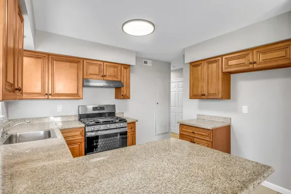 a kitchen with stainless steel appliances granite countertop a stove a sink and a microwave