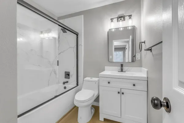 a bathroom with a toilet a sink a mirror and shower