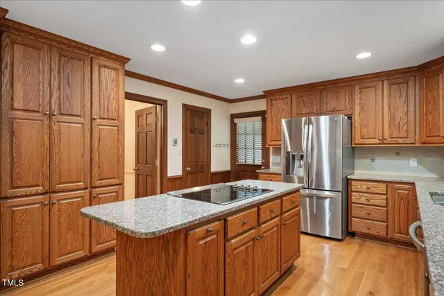 a kitchen with stainless steel appliances granite countertop a refrigerator a sink dishwasher and wooden cabinets with wooden floor