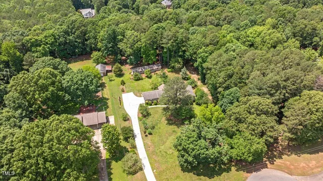 an aerial view of residential house with outdoor space and trees all around