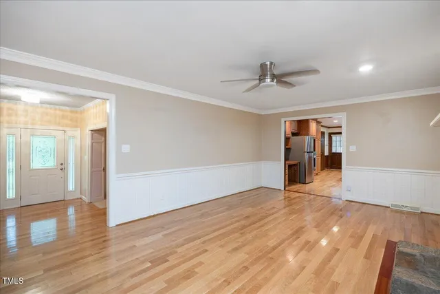 a view of an empty room with wooden floor and a ceiling fan