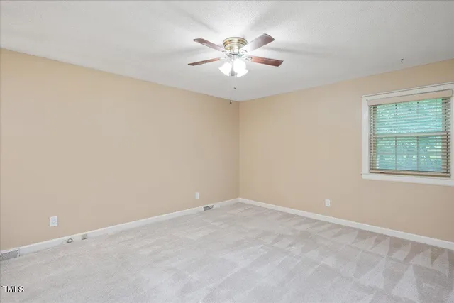 an empty room with chandelier fan and windows