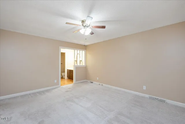 a view of an empty room with chandelier fan and a window