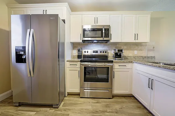 a kitchen with stainless steel appliances granite countertop a refrigerator stove and white cabinets