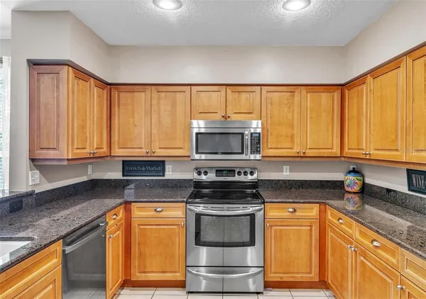 a kitchen with stainless steel appliances granite countertop a stove a sink and a microwave