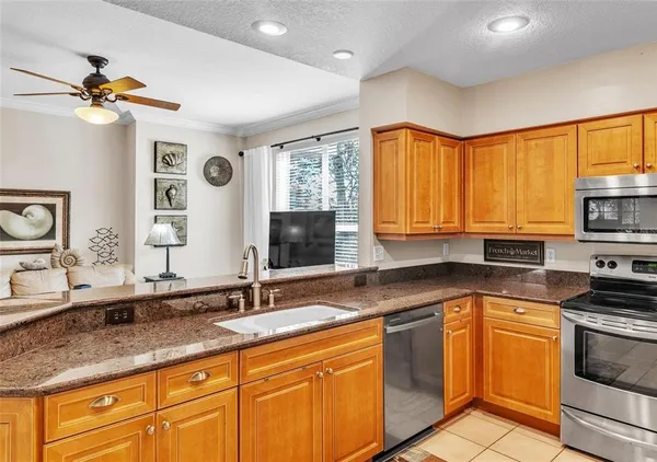 a kitchen with granite countertop a sink stainless steel appliances cabinets and a large window