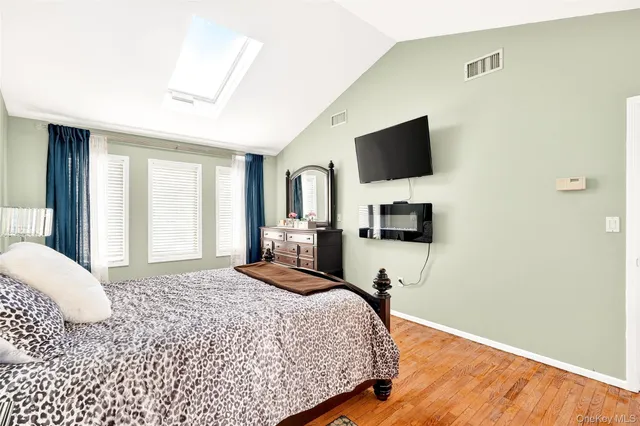 a bedroom with a bed painting on wall and a large window