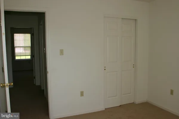 a view of an empty room with window and closet area