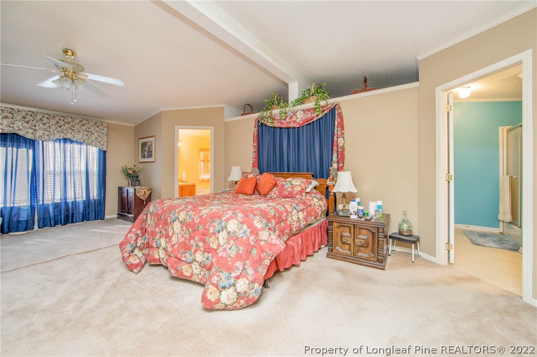5384 Wade-Stedman Road Wade, NC 28395 - Photo 14 of 18 a bed sitting in a spacious bedroom next to a window and a chandelier
