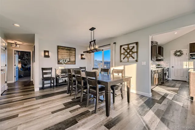 a view of a dining room and livingroom with furniture wooden floor a rug a painting and a chandelier