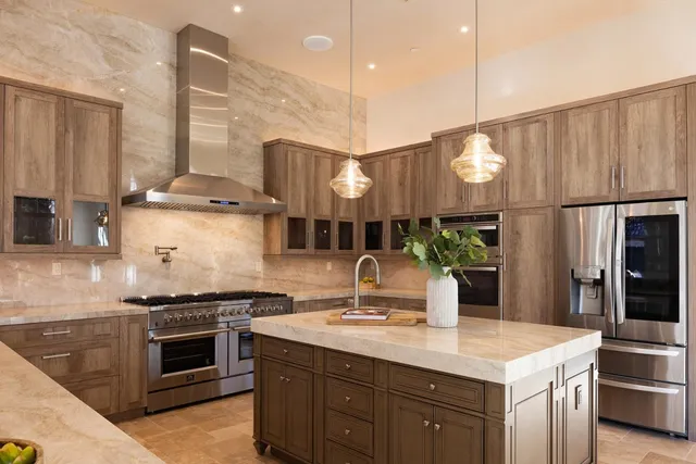 a kitchen with stainless steel appliances a sink a stove a refrigerator and cabinets