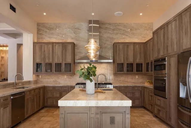 a kitchen with kitchen island granite countertop a sink stainless steel appliances and cabinets