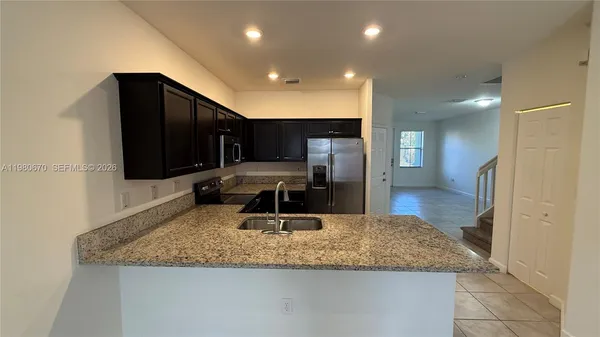 a kitchen with stainless steel appliances granite countertop a sink a stove and a refrigerator