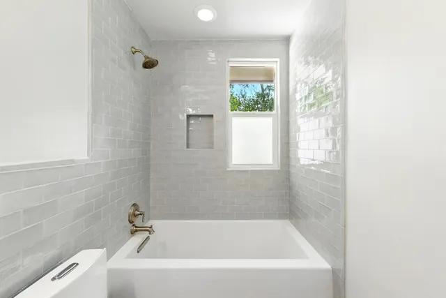 a white bath tub sitting in a bathroom next to a window