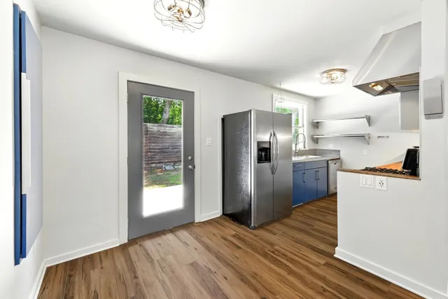 a kitchen with stainless steel appliances a refrigerator and a wooden floor