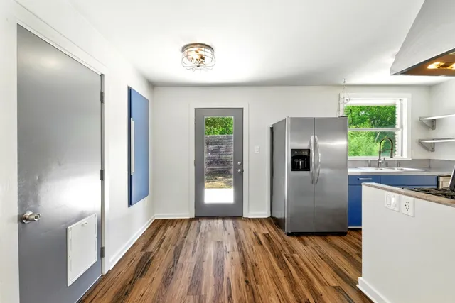 a kitchen with kitchen island wooden floors and refrigerator