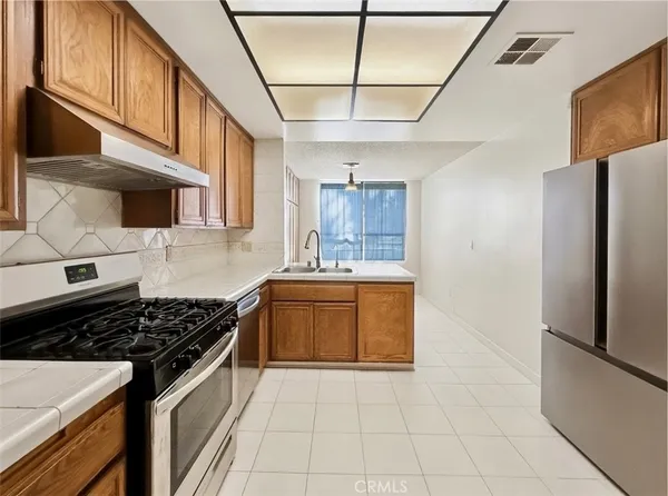 a kitchen with stainless steel appliances granite countertop a stove a sink and a refrigerator