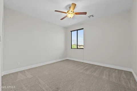 an empty room with a window and a fan