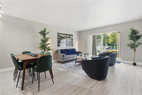 a living room with furniture a large window and a dining table