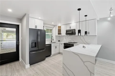 a kitchen with a refrigerator a microwave oven a sink and dishwasher with wooden floor