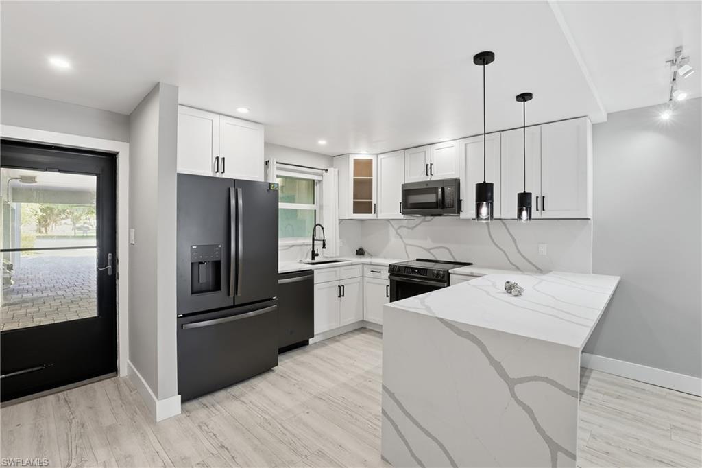 1320 Blue Point Avenue, Unit 2 Naples, FL 34102 - Photo 10 of 35 a kitchen with a refrigerator a microwave oven a sink and dishwasher with wooden floor