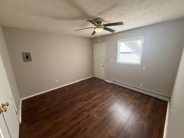 an empty room with wooden floor fan and windows