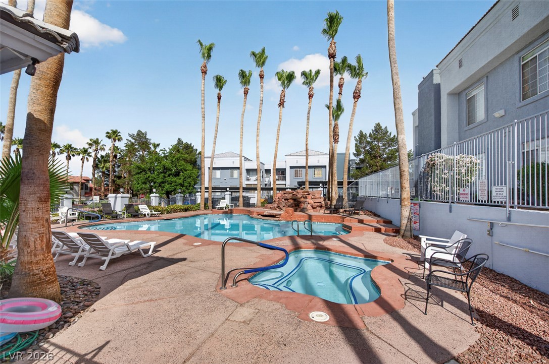 2201 Ramsgate Drive, Unit 1011 Henderson, NV 89074 - Photo 38 of 40 A refreshing pool and spa area with sun loungers beckons for relaxation amidst a palm-lined community setting.